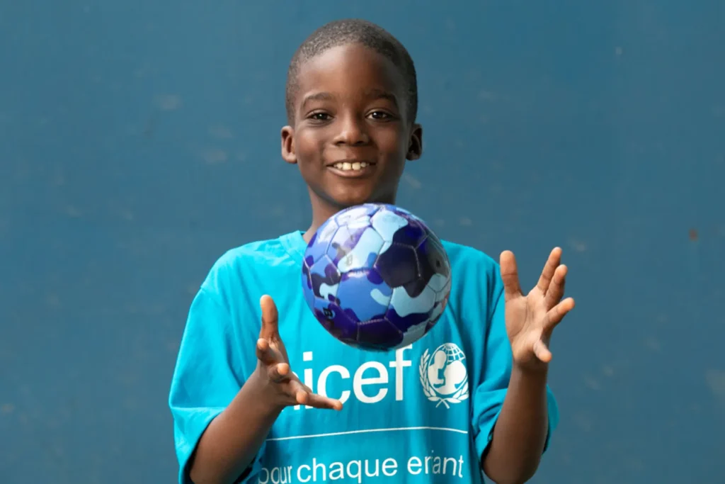 Kind met een Unicef shirt spelend met een bal